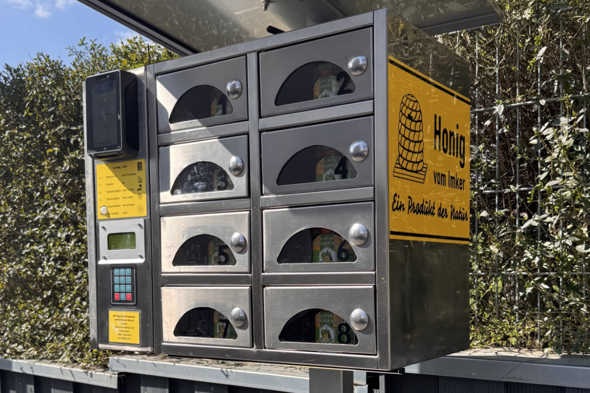 Selbstbedienungs-Honigautomat aus Edelstahl mit mehreren Fächern und Bezahlterminal.