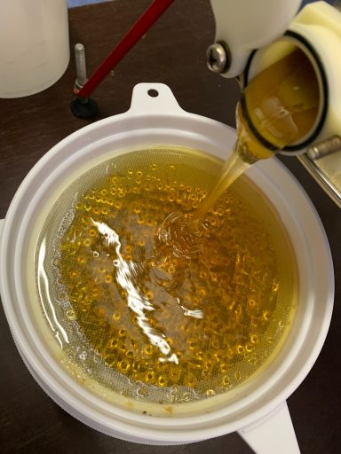 Honig läuft in Eimer mit Sieben