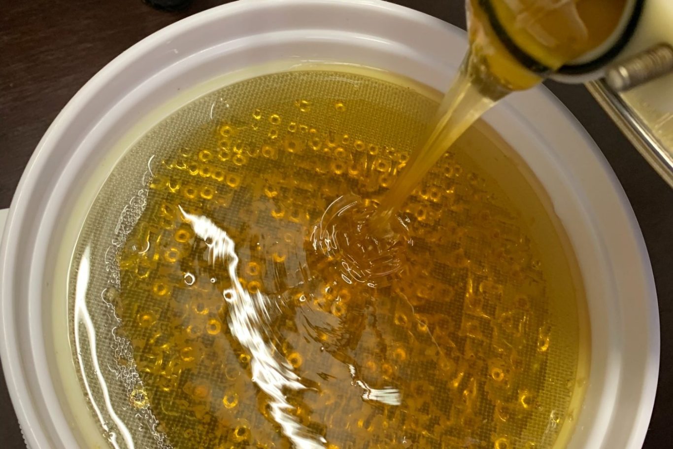 Honigschleuder mit rotem Handantrieb in einem warm beleuchteten, rustikalen Raum.